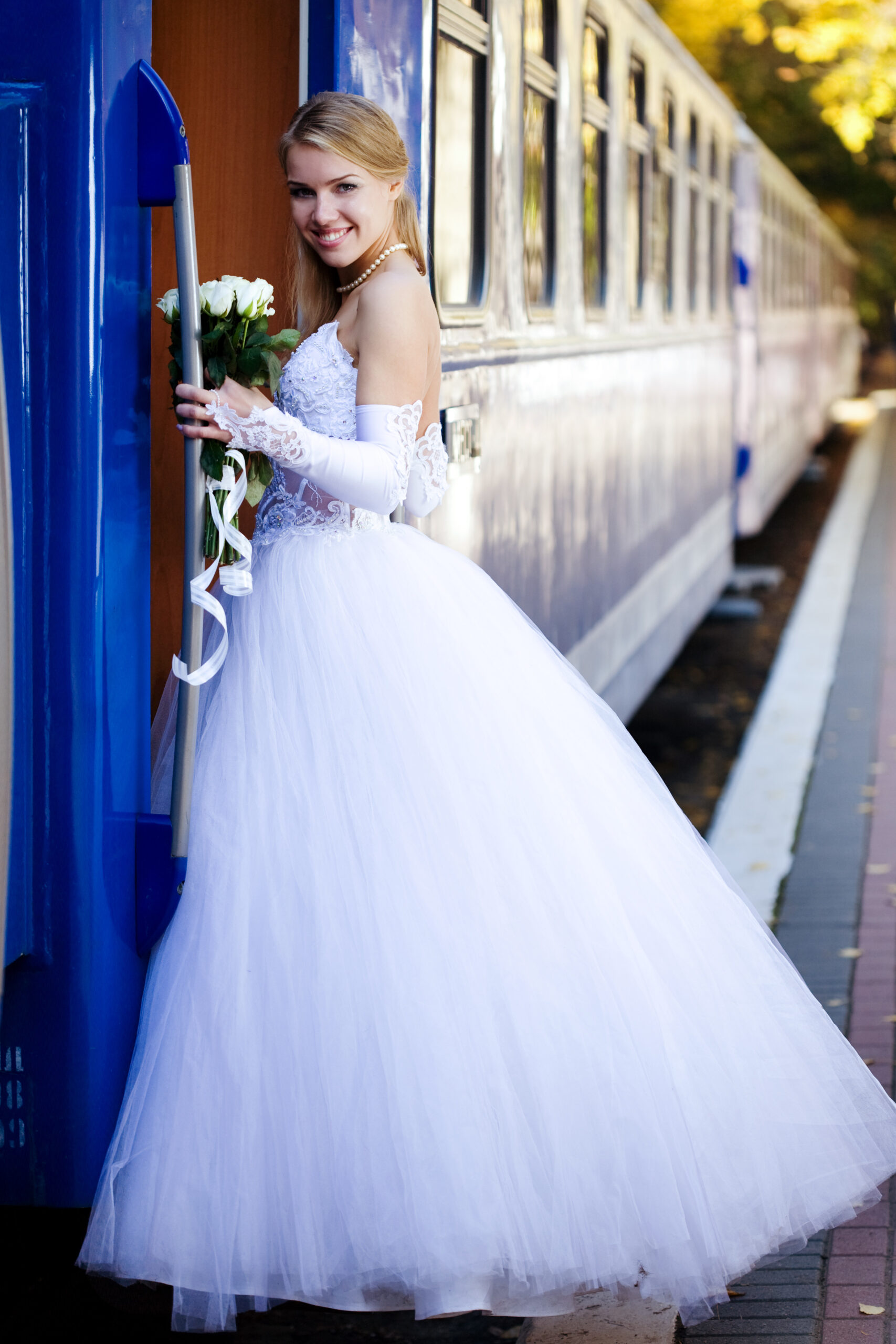 BLOG 3 Braut in einem weißen Kleid steigt in einen blauen Zug