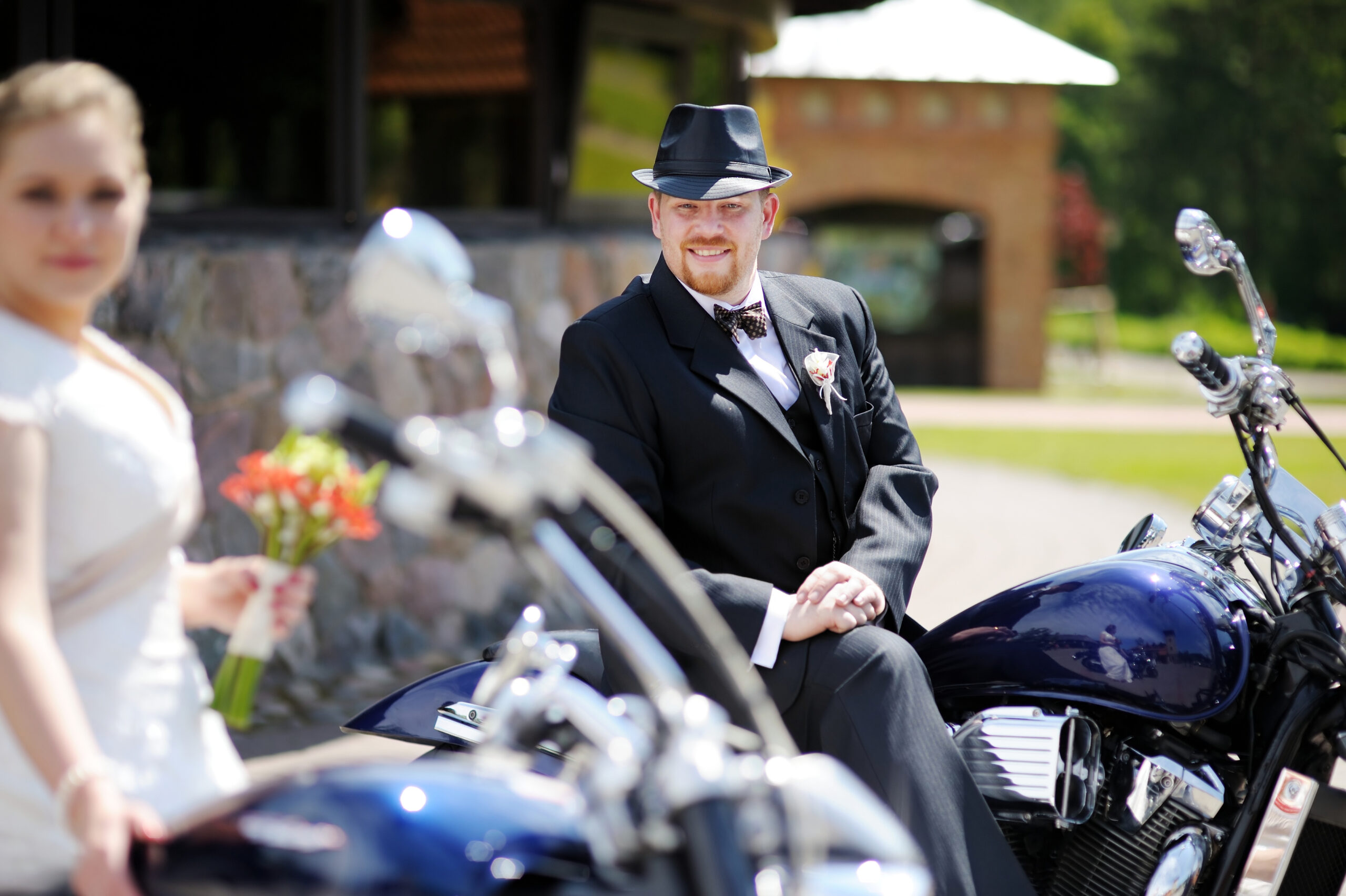 Brautpaar auf Motorrädern, festlich gekleidet.